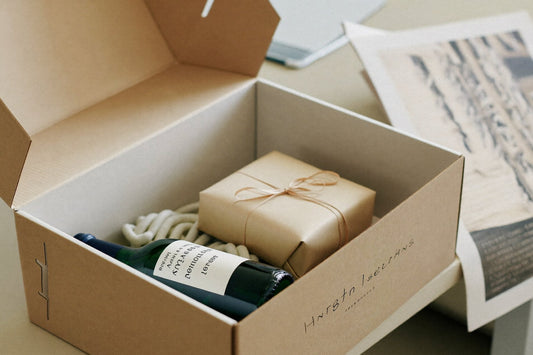 Geopende cadeaudoos met een fles wijn en een ingepakt cadeau