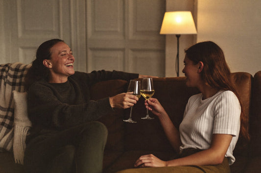 Twee vrouwen proosten met witte wijn op een bank